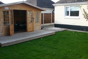 Une cabane en bois dotée d’une terrasse, d’un petit patio et d’une pelouse bien entretenue.