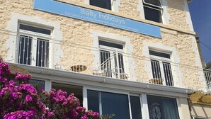Ein Gebäude mit einem Schild, auf dem „Salty Holidays“ steht, das Selbstversorger-Ferienwohnungen mit beeindruckendem Meerblick anbietet.