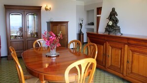 A dining area with a wooden table, chairs, a vase of flowers, and a statue on a cabinet.