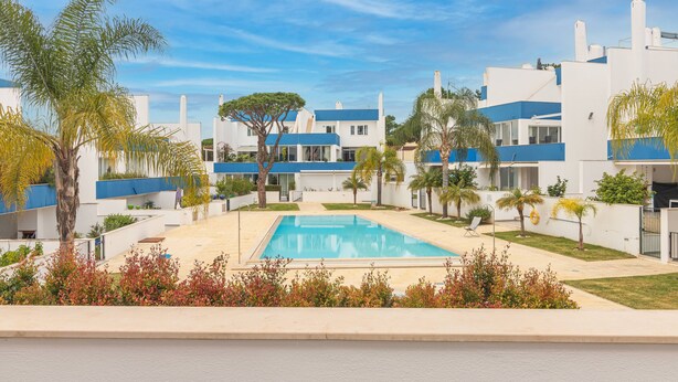 A modern hotel with a swimming pool, palm trees, and a clear blue sky. - Luxury Spacious 3 Bedroom Duplex Apartment With Sea Views & Salt Water Pool! (Loulé)