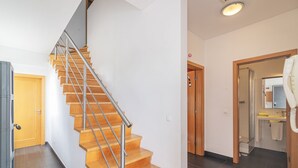A modern interior with a wooden staircase, a bathroom with a shower and sink, and a visible door leading to another room. - Luxury Spacious 3 Bedroom Duplex Apartment With Sea Views & Salt Water Pool! (Loulé)