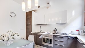 Una cocina moderna con armarios blancos, electrodomésticos de acero inoxidable y una zona de comedor con una mesa y sillas.