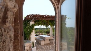 A patio area with a pergola, outdoor seating, and a view of a vineyard. - Stylish luxury trulli with private pool and amazing sea view  (Ostuni)