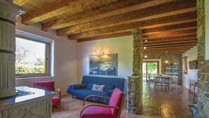 A spacious living area with a blue sofa, a red chair, and a stone column. - Capriva Del Friuli: House / Villa - Capriva del Friuli (Capriva del Friuli)