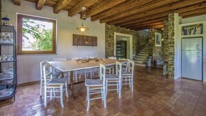 A rustic dining area with a wooden table and chairs, a stone wall, and a view of the outdoors. - Capriva Del Friuli: House / Villa - Capriva del Friuli (Capriva del Friuli)