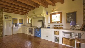 A spacious kitchen with wooden beams, a stone wall, and a chalkboard sign. - Capriva Del Friuli: House / Villa - Capriva del Friuli (Capriva del Friuli)