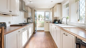 Een moderne keuken met witte kasten, een houten aanrechtblad en uitzicht naar buiten.