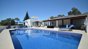 Ein Swimmingpool mit blauen Fliesen, Liegestühlen und Sonnenschirmen.
