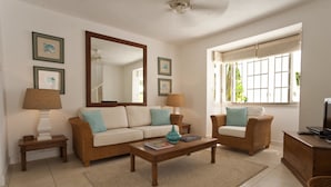 A living room with a sofa, two armchairs, a coffee table, a TV, and a large mirror. - Charming townhouse only 10 minutes from the beach! (Porters)