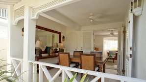 A dining area with a white railing, a table with chairs, and a ceiling fan. - Charming townhouse only 10 minutes from the beach! (Porters)
