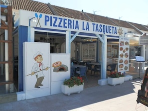 A pizzeria with outdoor seating and a pizza oven display.