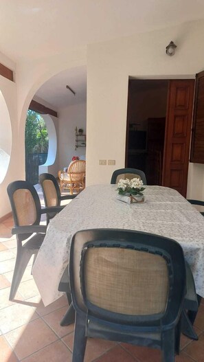 A dining area with a round table, chairs, and a flower centerpiece. - Independent villa with exclusive property garden (Solanas)