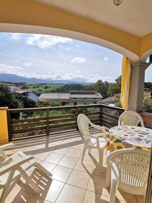 Enjoy the serene view of the surrounding hills from this balcony, featuring a comfortable seating area with a table.