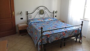 A bedroom with a metal bed frame, a wooden door, a bedside table, and a window with curtains. - Santa Caterina: apartments - 4 rooms - 4persons (Santa  caterina)
