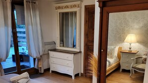 Ein Schlafzimmer mit Holzboden, einem Bett, einer Kommode, einem Spiegel und einem Nachttisch mit Lampe.