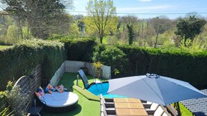 Ein Garten mit Pool, einer Holzterrasse und einer Sitzgelegenheit mit Tisch und Stühlen.