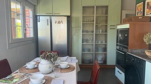 A dining area with a table set for two, a refrigerator, a microwave, and a washing machine. - Monte & Mar House (Camargo)