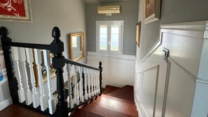 A staircase with a black and white balustrade, a wooden handrail, and a white door with a window at the top. - Monte & Mar House (Camargo)