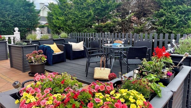 An outdoor patio with a seating area, planters with flowers, and a fence. - Monte & Mar House (Camargo)