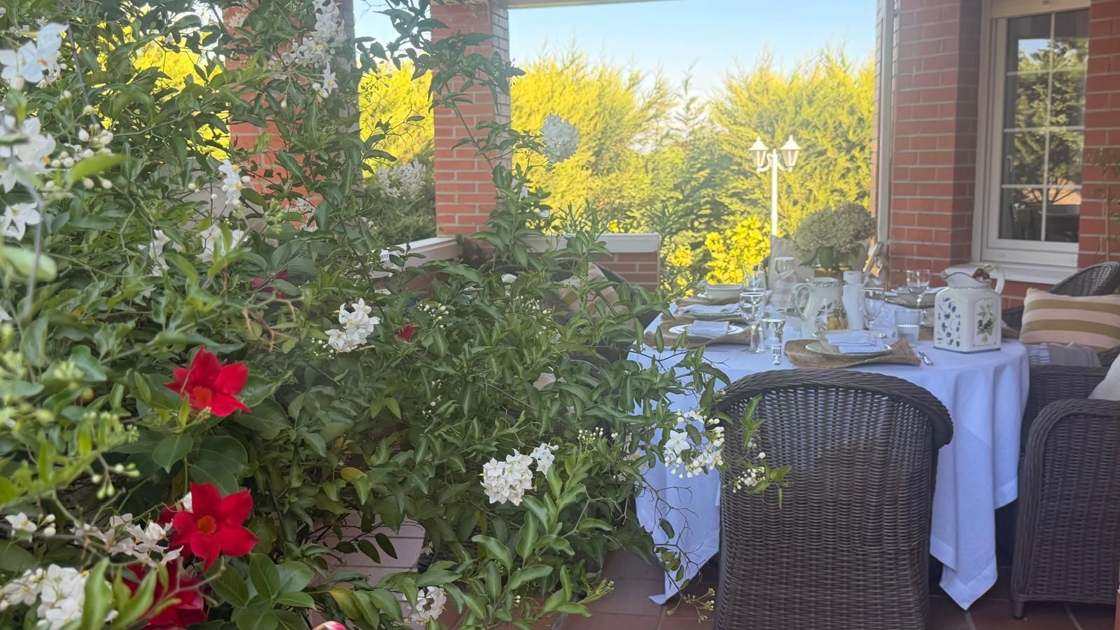 An outdoor dining area with wicker furniture and a table set for two.