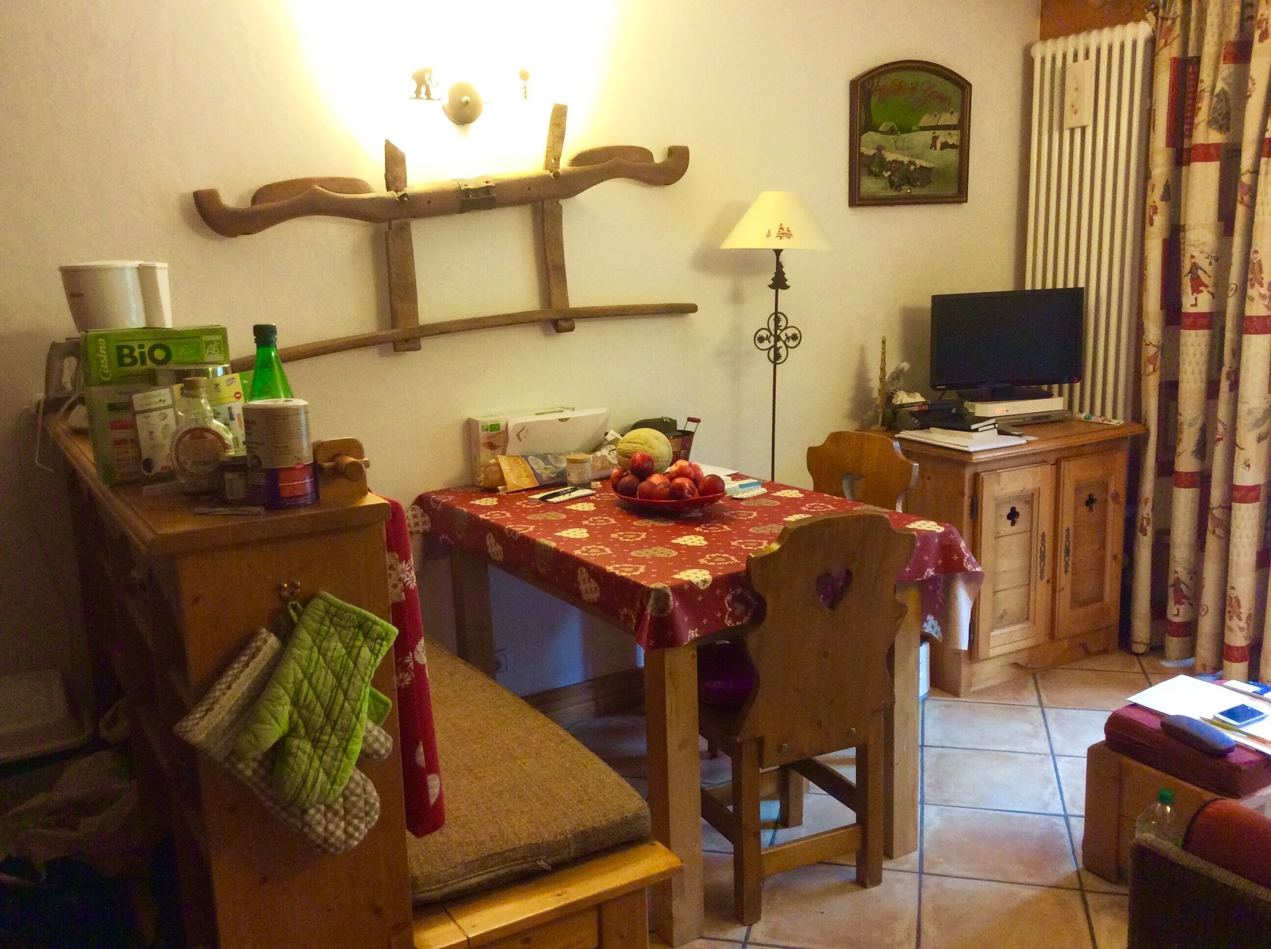 A cozy living room with a dining table, chairs, a television, and a radiator.
