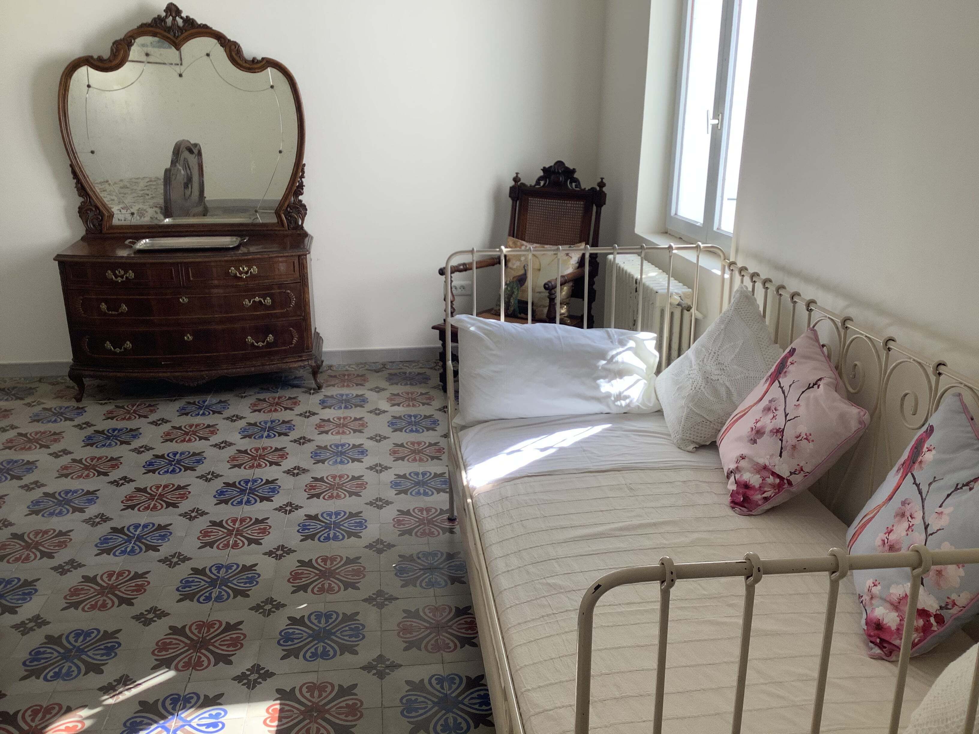 Une chambre à coucher avec un lit, une commode, un miroir et un radiateur.