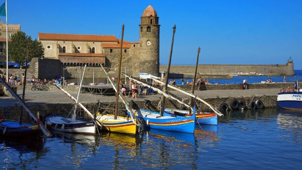 A harbor with boats docked, a stone tower, and a fortified wall. - Lovely house, garden with pool in tranquil village near coast and countryside (Raissac-D'aude)