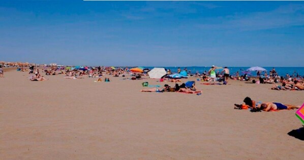 Guests can relax on the expansive beach with umbrellas for shade.