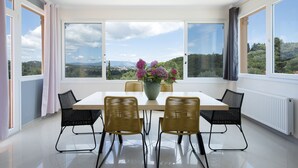 Un comedor con una mesa, sillas y un jarrón de flores.