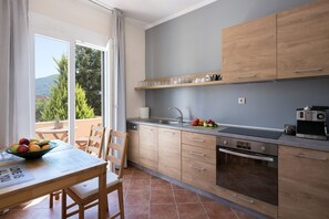 Une cuisine moderne avec des meubles en bois, un four encastré et un coin repas comprenant une table et des chaises.