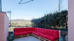 A red sectional sofa on a wooden platform in an outdoor patio area with a view of a hilly landscape. - Two steps outside 5 terre, Casa Sterinella !! (Follo Alto)