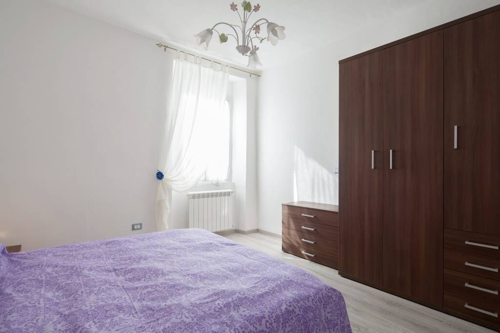 Ein Schlafzimmer mit einem Bett, einem Kleiderschrank und einem Fenster mit Vorhängen.