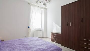 Ein Schlafzimmer mit einem Bett, einem Kleiderschrank und einem Fenster mit Vorhängen.
