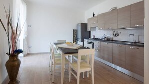 A modern kitchen with light wood cabinets, stainless steel appliances, and a dining area with a table and chairs. - Two steps outside 5 terre, Casa Sterinella !! (Follo Alto)