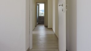 A hallway with a wooden floor leading to a door with a view of a building outside. - Two steps outside 5 terre, Casa Sterinella !! (Follo Alto)