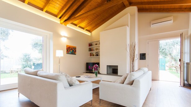Een ruime woonkamer met een hoge plafond, witte banken, een flatscreen-tv en een open haard.