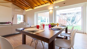 Een moderne eetruimte met een houten plafond, grote ramen en uitzicht op de omgeving.