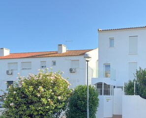 Un immeuble d’habitation avec un toit recouvert de tuiles rouges, des murs blancs et de nombreuses fenêtres.