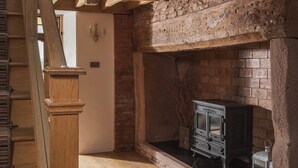 A staircase with wooden railings leading to a loft area with exposed wooden beams and a stone fireplace. - Luxury Farmhouse with Stunning Somerset Views (Taunton)