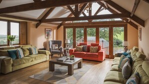 A spacious living room with wooden beams, large windows, and a view of the outdoors. - Luxury Farmhouse with Stunning Somerset Views (Taunton)