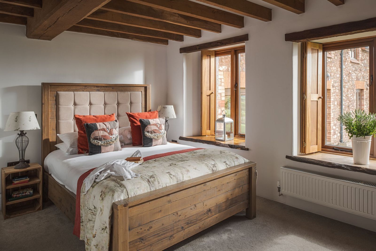 Une chambre avec un lit en bois, une table de chevet, une fenêtre donnant sur l’extérieur et un radiateur.