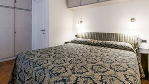 A bedroom with a patterned bedspread, a white door, and a nightstand with a lamp. - Venice historic center 5 minutes from the Rialto Bridge (Venezia)