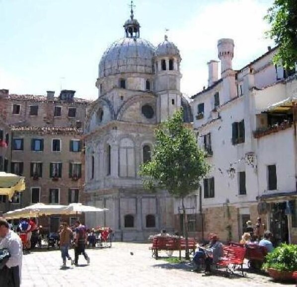 A historic building with a dome and bell tower, surrounded by a cobblestone square with outdoor seating and pedestrians. - Venice historic center 5 minutes from the Rialto Bridge (Venezia)