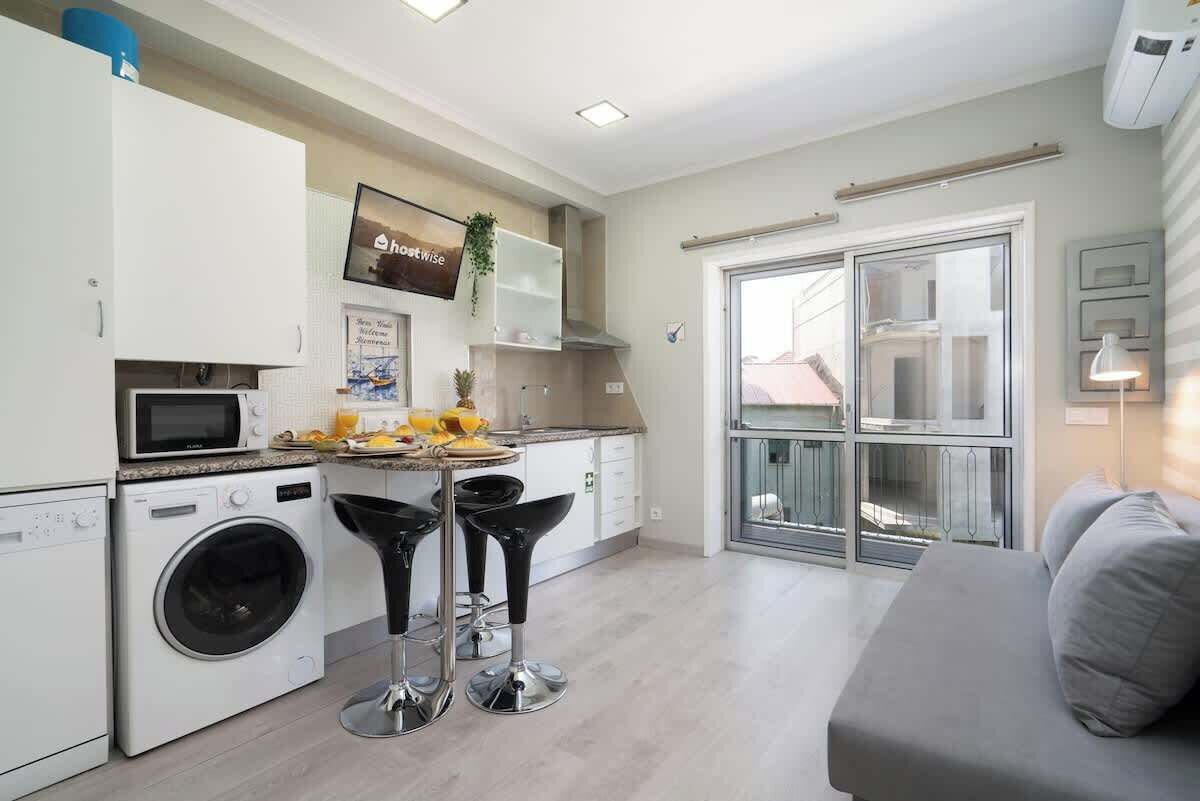 Une cuisine moderne équipée d’un lave-linge, d’un four à micro-ondes et de tabourets de bar.