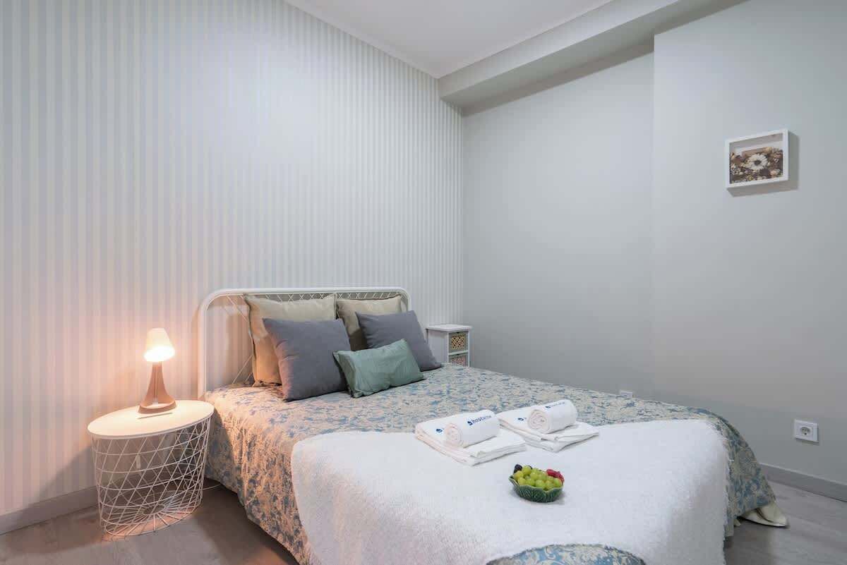 Un dormitorio ordenado con cama, mesita de noche y un cuadro en la pared.