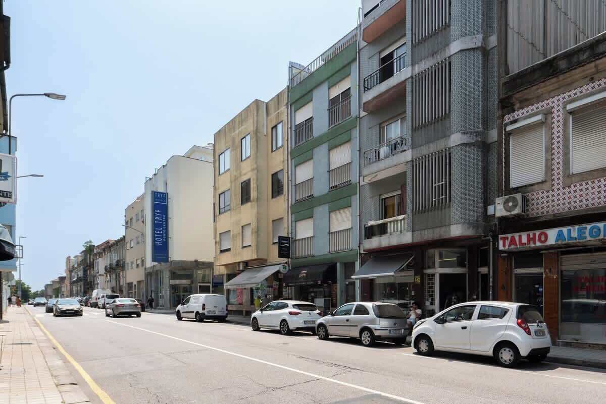 A street view with multi-story buildings, a hotel sign, and parked cars.