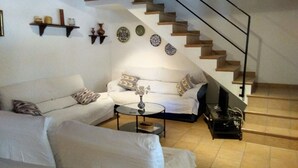 Un salon avec un canapé blanc, une table basse et un escalier avec des marches en bois.