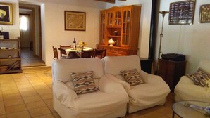 Un salon avec deux canapés blancs, un meuble en bois et une table à manger avec des chaises.