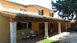 Un bâtiment à deux étages doté d’un patio couvert, de colonnes en pierre et d’un toit en tuiles.