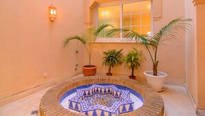 A courtyard with a tiled fountain, potted plants, and a window with warm lighting. - 75m to Beach Luxury 4-Bed Villa with Heated Pool & Oasis Patio in Marbella (Marbella)
